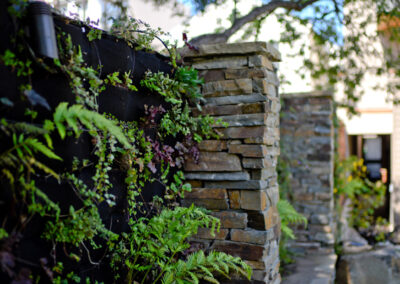 Green wall set between stacked-stone columns.